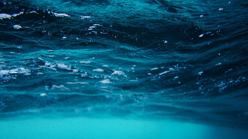 Serene underwater view of sea surface with vibrant turquoise and blue waves.